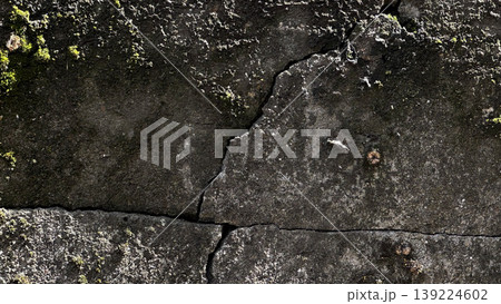 Close-up of a weathered wall featuring cracks and moss. 139224602