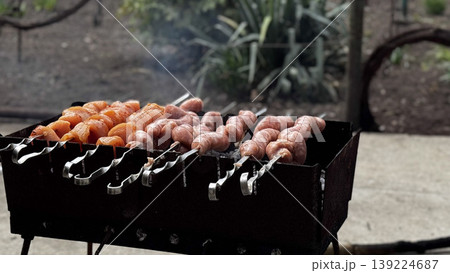 Mouthwatering sausages and vegetables sizzling on a grill. 139224687