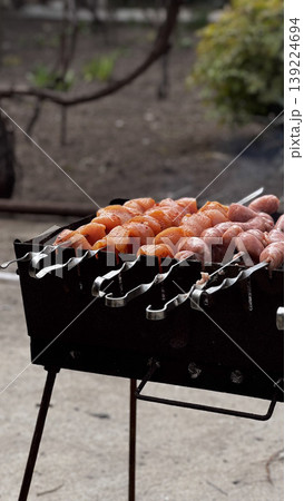 Juicy skewers sizzling on a barbecue grill in a garden setting. 139224694
