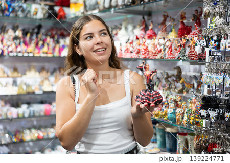 Female buyer holds in hands tests figurine she-dancer flamenco in memorable gifts shop 139224771