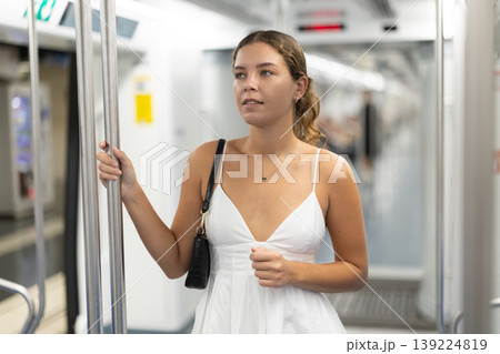 Calm young girl standing on wagon travelling by subway Calm young girl standing on wagon travelling by subway 139224819