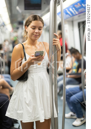Positive young girl standing on wagon holding phone in hand Positive young girl standing on wagon holding phone in hand 139224827