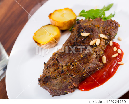 Beef steak with ketchup and pine nuts, served with potatoe 139224920