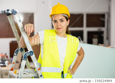 Portrait of woman builder in protective helmet and vest 139224964