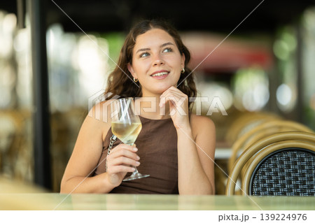 Woman sitting in a cafe with a glass of wine 139224976