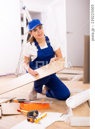 Woman builder preparing laminated boards for laying floors Woman builder preparing laminated boards for laying floors 139225005