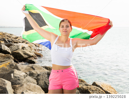 Young woman on coast posing with flag of South Africa Young woman on coast posing with flag of South Africa 139225028