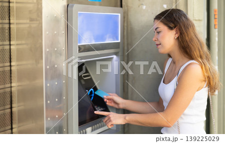 Girl uses ATM, withdraws cash from card Girl uses ATM, withdraws cash from card 139225029