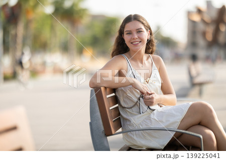 Portrait of girl relaxing on bench in summer city park Portrait of girl relaxing on bench in summer city park 139225041