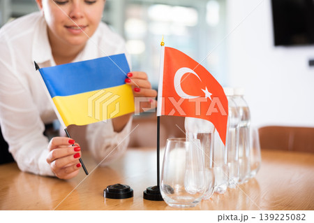 Little flag of Turkey on table and flag of Ukraine put next to it by young woman Little flag of Turkey on table and flag of Ukraine put next to it by young woman 139225082