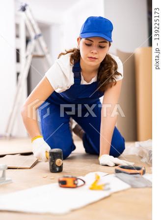 Woman builder puts laminate on the floor in room Woman builder puts laminate on the floor in room 139225173