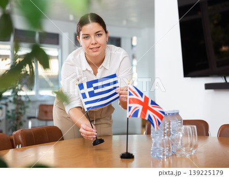 Young woman puts flags of Greece and Great Britain on table Young woman puts flags of Greece and Great Britain on table 139225179