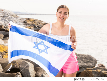 Young woman on coast posing with flag of Israel Young woman on coast posing with flag of Israel 139225187