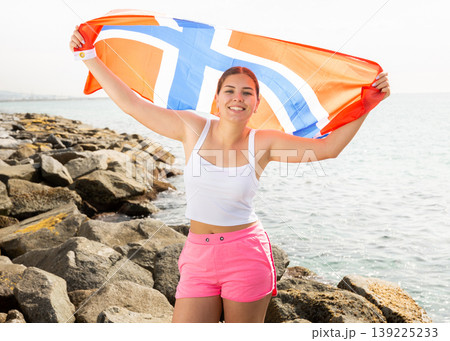 National flag of Norway. Beautiful woman with Norway flag on seashore National flag of Norway. Beautiful woman with Norway flag on seashore 139225233