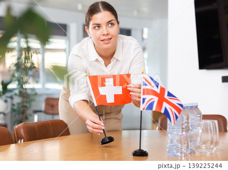 Female secretary places flags of the Switzerland and Great Britain on the table before negotiations of top political figures Female secretary places flags of the Switzerland and Great Britain on the table before negotiations of top political figures 139225244