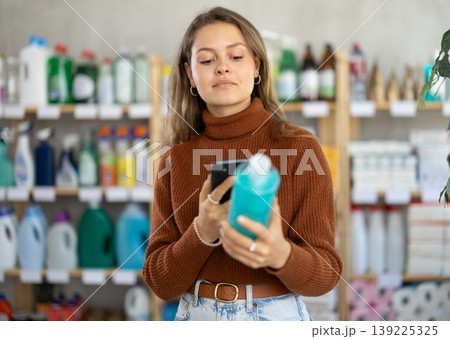 Young woman scanning QR-code on shampoo in department store 139225325