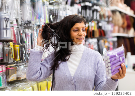 Smiling latina choosing hair rollers in store Smiling latina choosing hair rollers in store 139225402