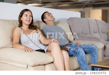 Young woman with husband testing sofa in furniture salon 139225572