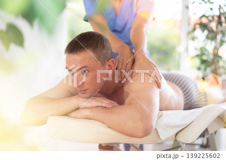 Cropped circumcised woman performs back massage to male client 139225602