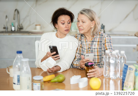 Two careful women scanning different products using their smartphones Two careful women scanning different products using their smartphones 139225720