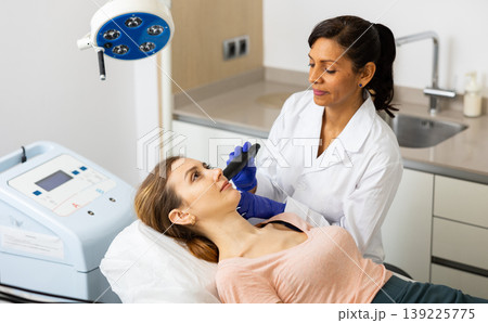 Hispanic woman beautician doing needle-free mesotherapy for young woman 139225775