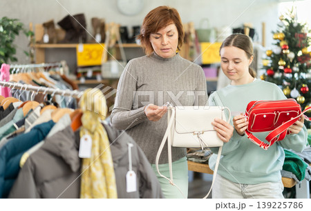 Teen girl with mum picks up clothes and choose handbag, New Year Eve sale 139225786