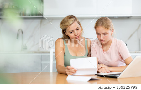 Upset teenage girl reading letter about exam results with concerned mother Upset teenage girl reading letter about exam results with concerned mother 139225799