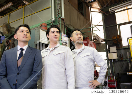 工場で未来を笑顔の横顔で見つめる、見上げるビジネスマンと作業員と3人チームの信頼、信金営業や商工会 139226643