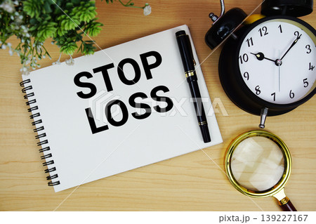 Stop Loss text written on notepad with alarm clock and magnifying glass flat lay on wooden background 139227167