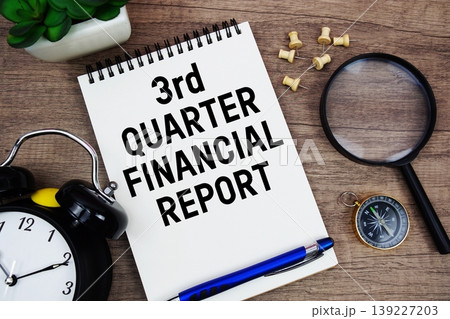 3rd Quarter Financial Report text written on notepad with alarm clock, compass and magnifying glass flat lay on wooden background 139227203