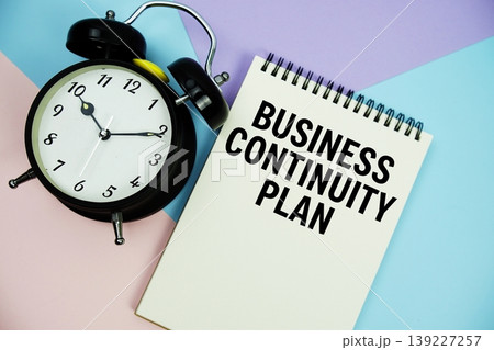 Business Continuity Plan text written on notepad with alarm clock flat lay on multicolor pastel background 139227257