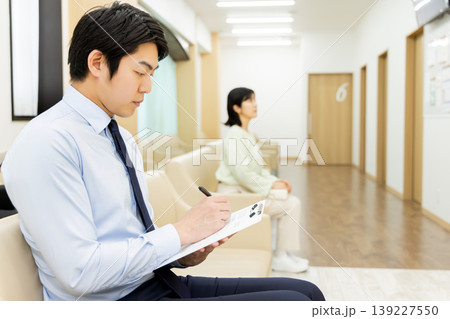 病院の待合室で問診票を記入するビジネスマン 139227550