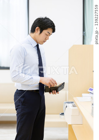 病院の受付で支払いをするビジネスマン 139227559