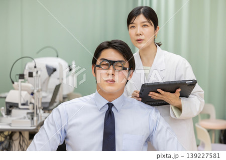 視力検査を受ける男性患者とタブレットで記録する女性医師 視力検査を受ける男性患者とタブレットで記録する女性医師 139227581