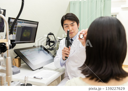 ペンライトで目の状態を診察する眼科医と女性患者の診療シーン(モニターはテスト画面のはめ込み) ペンライトで目の状態を診察する眼科医と女性患者の診療シーン(モニターはテスト画面のはめ込み) 139227629