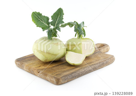 Fresh kohlrabi vegetables with green leaves on a rustic wooden cutting board 139228089