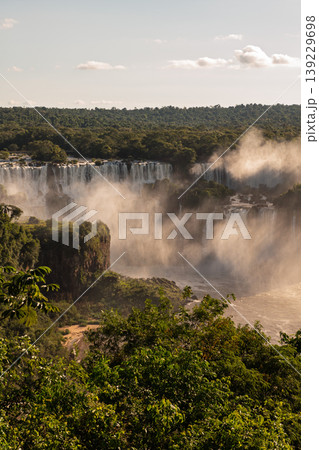 Breathtaking majestic iguazu falls cascading water into lush green forest with heavy mist Breathtaking majestic iguazu falls cascading water into lush green forest with heavy mist 139229698