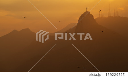 Serene sunset silhouette of Christ Redeemer over mountain in Rio de Janeiro Brazil creating peaceful view 139229725
