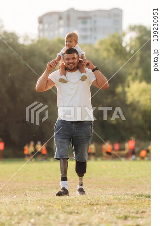 The amputee father is with his son on the field The amputee father is with his son on the field 139230951