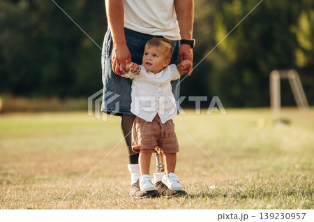 Fresh air, nature, holding kid by hands. The amputee father is with his son on the field Fresh air, nature, holding kid by hands. The amputee father is with his son on the field 139230957