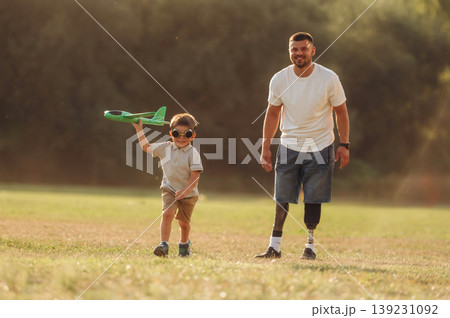 Active, running with toy plane. The amputee father is with his son on the field Active, running with toy plane. The amputee father is with his son on the field 139231092
