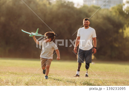 Active, running with toy plane. The amputee father is with his son on the field Active, running with toy plane. The amputee father is with his son on the field 139231095