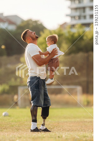Feeling good, holding kid in hands. The amputee father is with his son on the field 139231155
