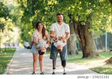 Front view, having a walk. Family of father that is amputee with prosthesis, mother and two kids 139231181