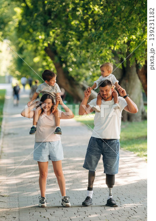 Front view, having a walk. Family of father that is amputee with prosthesis, mother and two kids 139231182