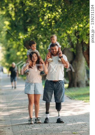 Front view, having a walk. Family of father that is amputee with prosthesis, mother and two kids Front view, having a walk. Family of father that is amputee with prosthesis, mother and two kids 139231184