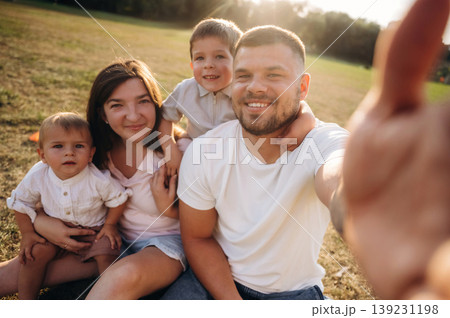 Selfie time, sitting. Mother, amputee father with prosthesis and kids are on the field Selfie time, sitting. Mother, amputee father with prosthesis and kids are on the field 139231198