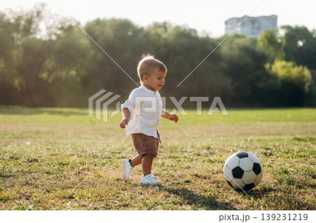 Little boy is playing soccer on the field under the sunlight 139231219