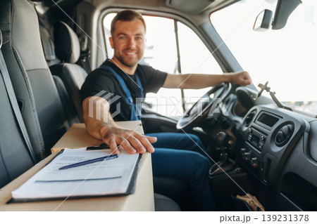 Just formal stuff, the notepad with document, invoice. Inside of the bus with delivery service man in uniform Just formal stuff, the notepad with document, invoice. Inside of the bus with delivery service man in uniform 139231378