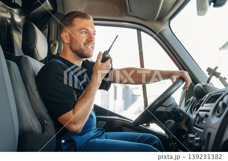 Talking by using walkie talkie. Inside of the bus with delivery service man in uniform Talking by using walkie talkie. Inside of the bus with delivery service man in uniform 139231382